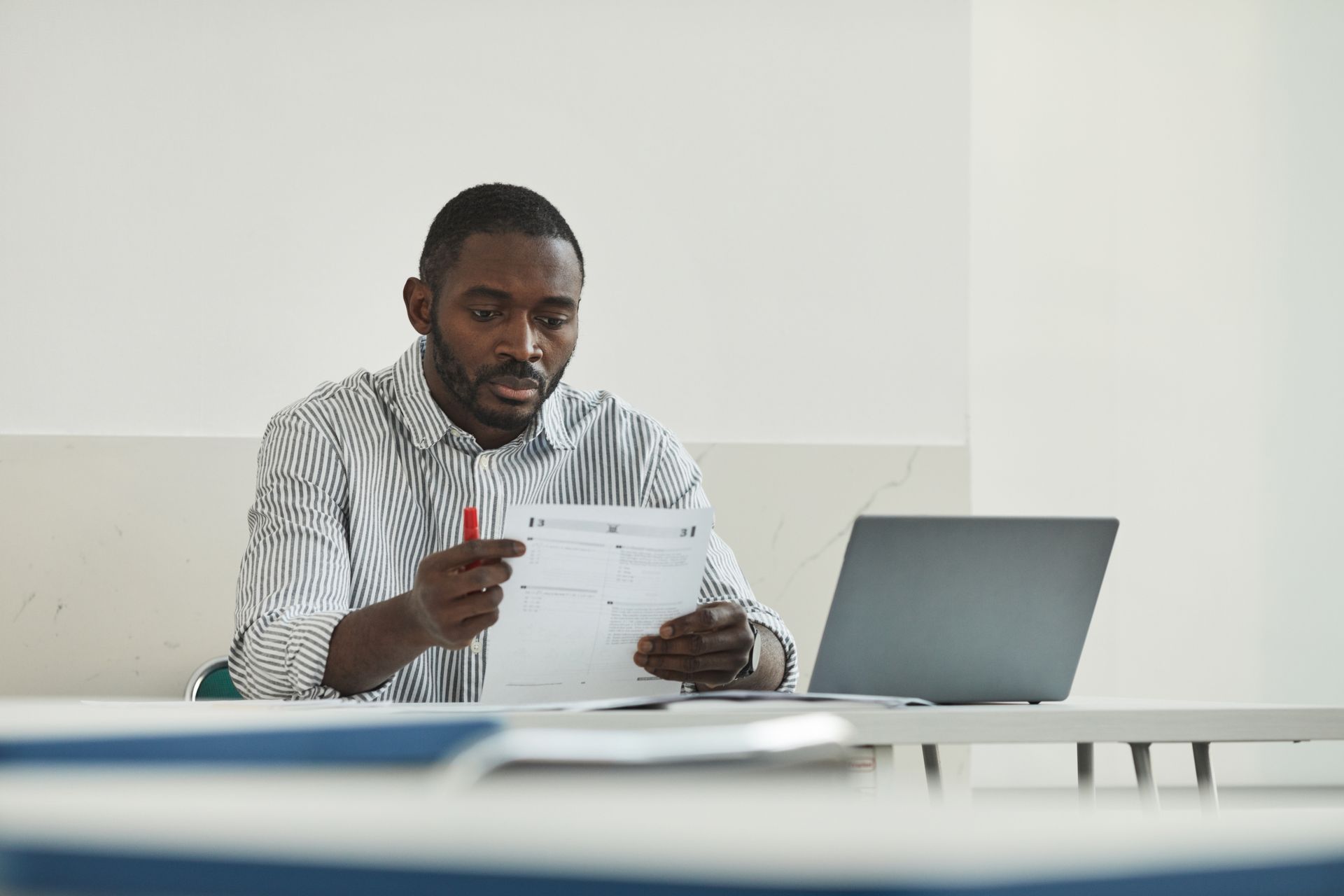 Business professional reviewing financial documents beside a laptop