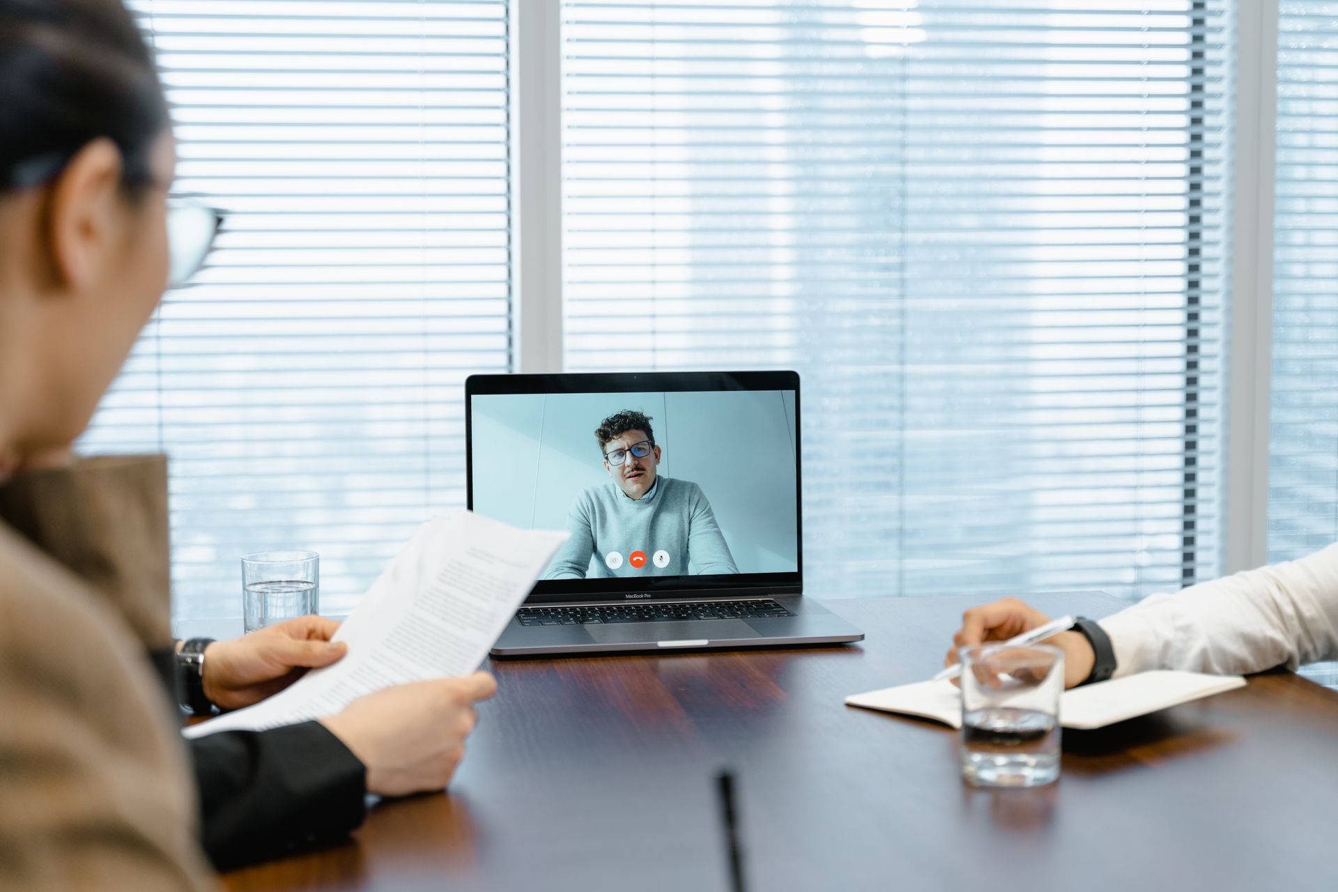 Two professionals in a meeting room conducting a virtual CFO video call on a laptop