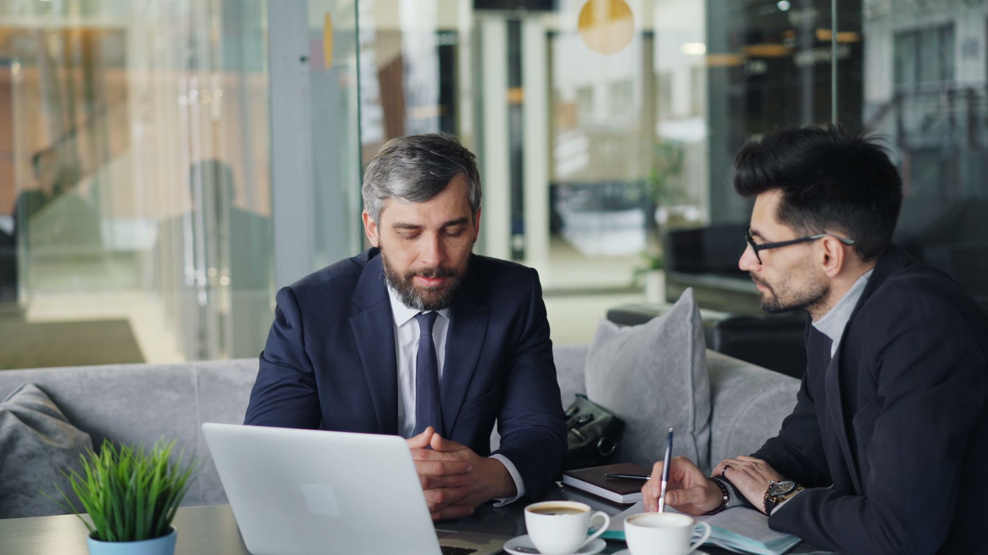 Corporate tax consultant advising a business client over a laptop in an office